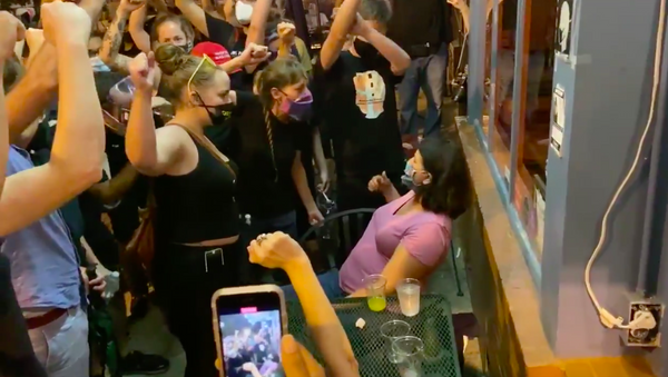 Manifestantes agresivos intimidan a una mujer en un restaurante en Washington - Sputnik Mundo