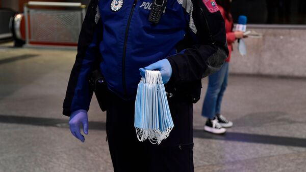 Un Policía reparte mascarillas en la estación de Atocha de Madrid - Sputnik Mundo