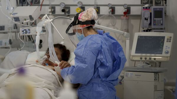 Una trabajadora de la salud atiende a un paciente en una unidad de cuidados intensivos designada para personas infectadas con coronavirus en un hospital en Buenos Aires (Argentina) - Sputnik Mundo