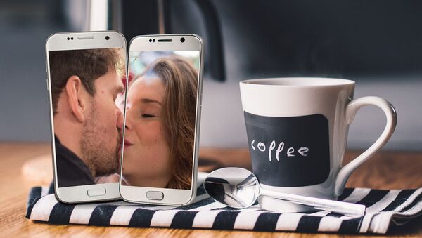 Dos móviles muestran a una mujer y un hombre besándose - Sputnik Mundo