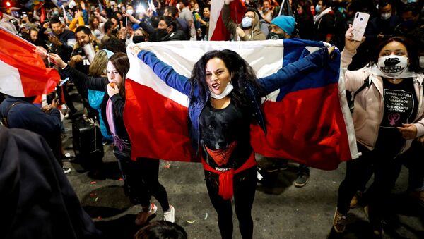 A woman holds a Chilean flag as she reacts to the referendum on a new Chilean constitution in Valparaiso - Sputnik Mundo