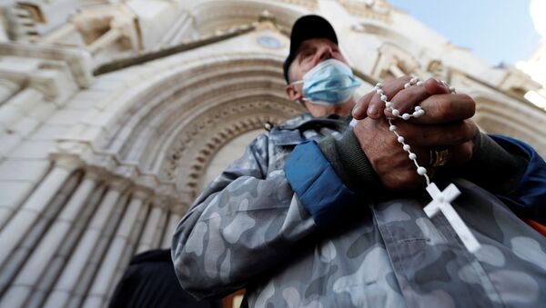 Un hombre reza frente a la iglesia de Notre Dame en Niza, Francia - Sputnik Mundo