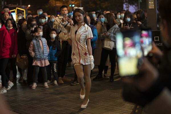 Девушка в костюме медсестры выступает перед толпой в ночь Хэллоуина в торговом районе Пекина - Sputnik Mundo