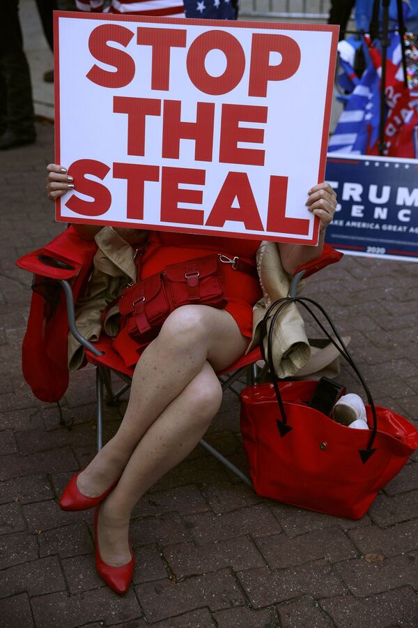 Демонстрант держит табличку с надписью «Остановите воровство» возле конференц-центра в Филадельфии - Sputnik Mundo