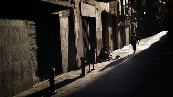 Una mujer pasa junto a un hombre que pide limosna en una calle del centro de Barcelona - Sputnik Mundo