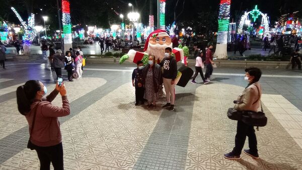 Familias sacándose fotos junto a un muñeco de Papa Noel, en la plaza 14 de Septiembre - Sputnik Mundo
