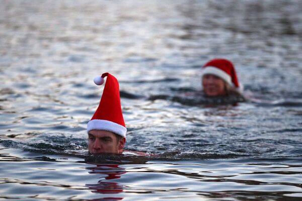 Las personas, que se han puesto las gorras de Navidad, se bañan en el lago Serpentine en Hyde Park en Londres, Reino Unido. - Sputnik Mundo