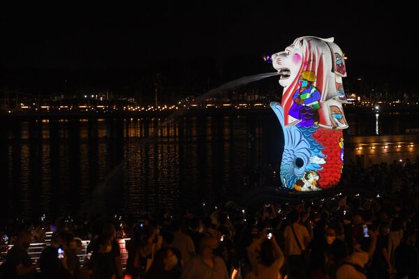 Unas personas se reúnen para ver la iluminación de una de las tradicionales estatuas de Merlión, la mascota oficial de Singapur, en las celebraciones de Nochevieja en el país asiático. - Sputnik Mundo