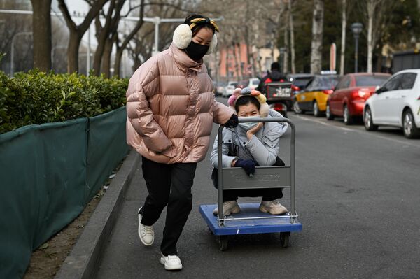 Una mujer lleva a su amiga en un carrito a lo largo de una carretera en Pekín el 28 de diciembre de 2020. - Sputnik Mundo
