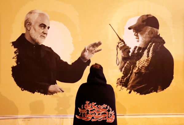 Una mujer observa las fotos de Soleimani y Muhandis a un año de sus muertes. - Sputnik Mundo
