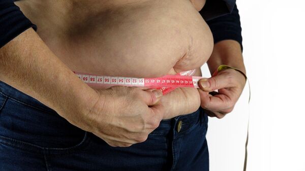 Una persona se mide la barriga con una cinta métrica - Sputnik Mundo