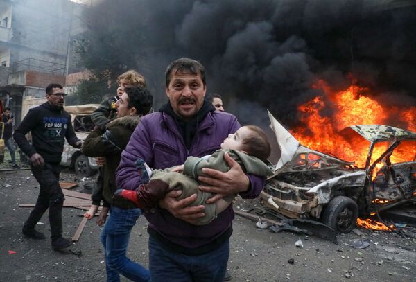 Un hombre carga a un bebé después de que un coche bomba explotara en el centro de la ciudad siria de Azaz, el 31 de enero. - Sputnik Mundo