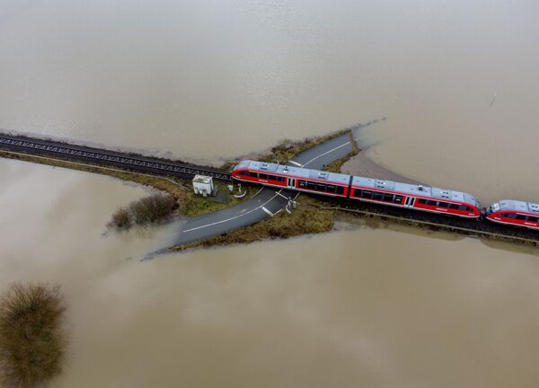 Un tren pasa por un cruce ferroviario rodeado por inundaciones en Nidderau (Alemania), el 3 de febrero. - Sputnik Mundo
