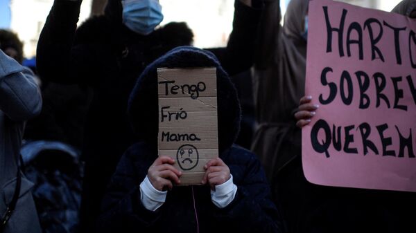 Una niña lleva un cartón que dice Tengo frío, mamá durante una manifestación contra los cortes de luz frente a la sede del gobierno regional en Madrid. 3 de diciembre de 2020. - Sputnik Mundo