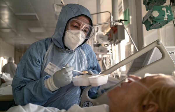 Una enfermera da de comer a un paciente con COVID-19 en la unidad de cuidados intensivos de un hospital moscovita. - Sputnik Mundo