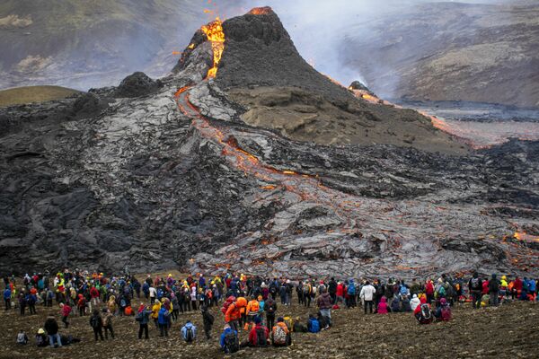 Los turistas observan la lava que sale de la boca del volcán Fagradalsfjall en Islandia. - Sputnik Mundo