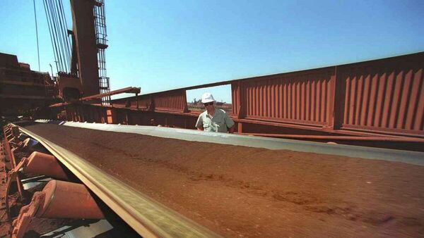 Un trabajador observa una cinta transportadora mientras se extrae mineral de hierro de la Zona Minera C en Pilbara (Australia Occidental) - Sputnik Mundo