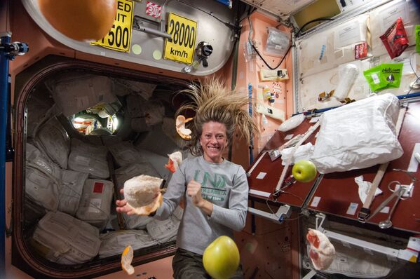 La astronauta de la NASA Karen Nyberg, ingeniera de vuelo de la Expedición 36, cerca de la fruta fresca que flota libremente en el nodo Unity de la Estación Espacial Internacional.  - Sputnik Mundo