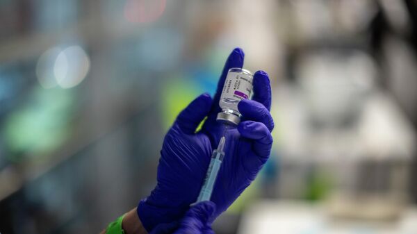 Un trabajador de la salud sostiene un vial de la vacuna AstraZeneca - Sputnik Mundo