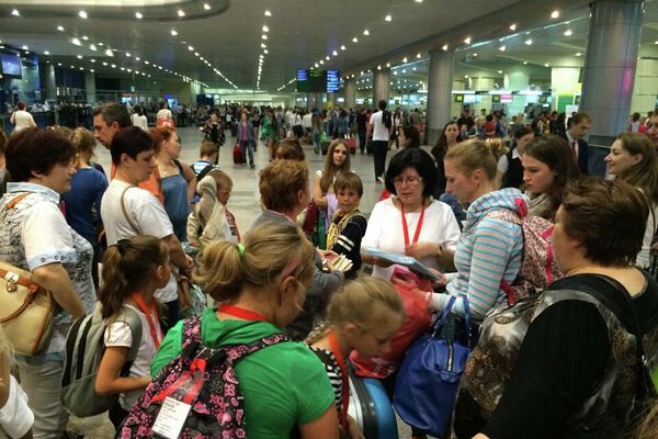 Los niños de Chernóbil con sus familias rusas en el aeropuerto Domodedovo de Moscú antes de ir a Galicia con Ledicia Cativa - Sputnik Mundo