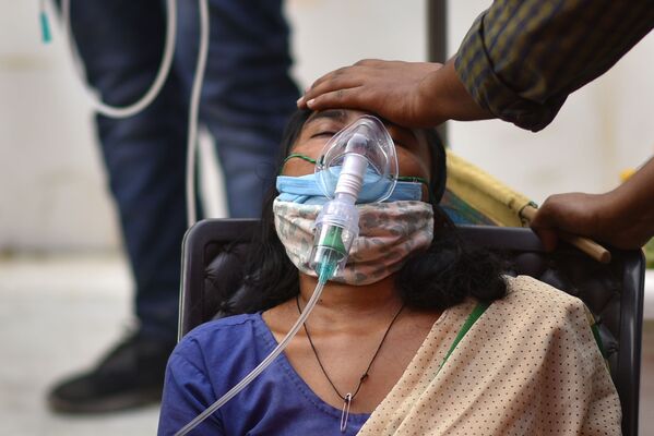 Tras los primeros éxitos en la lucha contra el COVID-19, el segundo país con más habitantes del mundo experimentó un rápido retroceso, y empezó a empeorar. Ahora, se detectan diariamente más de 350.000 contagios. En la foto: una mujer con problemas para respirar recibe oxígeno en el principal templo sij de la ciudad de Delhi, el Gurdwara Bangla Sahib. - Sputnik Mundo