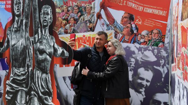 La gente se toma fotos frente a los carteles soviéticos para la fiesta del 1 de mayo - Sputnik Mundo
