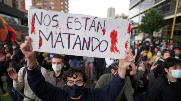 Un manifestante colombiano con un cartel que dice nos están matando. - Sputnik Mundo