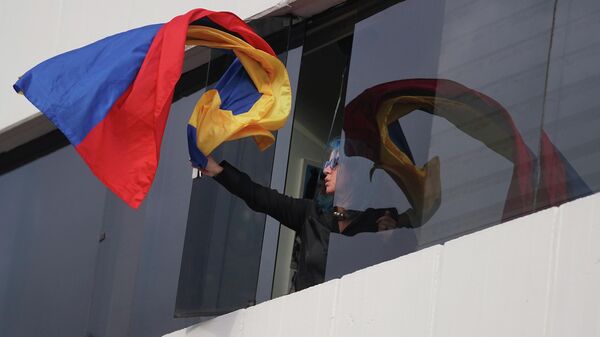 Una mujer saca una bandera de Colombia por la ventana durante las protestas en Colombia - Sputnik Mundo
