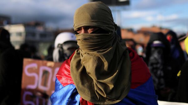 Un manifestante encapuchado y con la bandera de Colombia durante una protesta en Bogotá - Sputnik Mundo