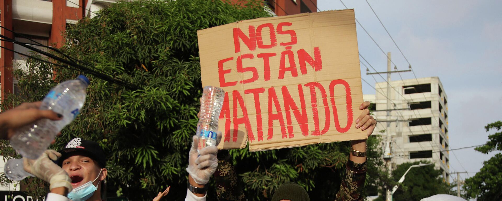 Un manifestante sostiene una pancarta que dice 'nos están matando' frente al estadio Romelio Martínez en Barranquilla. 13 de mayo de 2021 - Sputnik Mundo, 1920, 19.05.2021