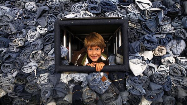 Эрек Хэнсон, 9 лет, из Кертиса, штат Огайо, высовывает голову из витрины с 33 088 парами джинсов, которые были собраны журналом National Geographic Kids для переработки в теплоизоляционный материал для жилья в Вашингтоне, 2009 год - Sputnik Mundo