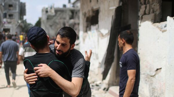 Палестинцы обнимаются друг с другом после возвращения в свои разрушенные дома после перемирия между Израилем и ХАМАС в Бейт-Хануне  - Sputnik Mundo