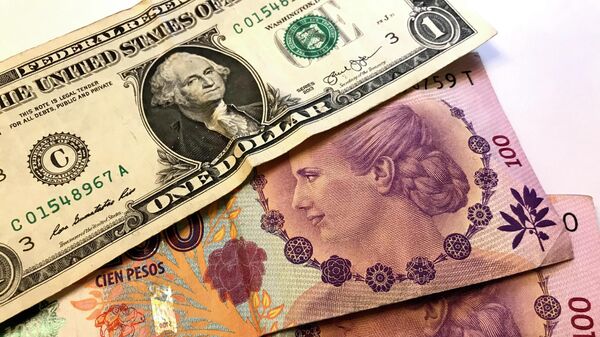 Pesos argentinos y un billete de dólar - Sputnik Mundo