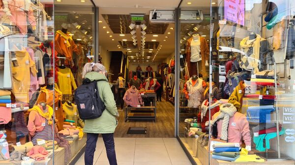Una mujer viendo ropa en una tienda - Sputnik Mundo