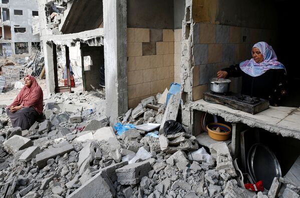 Una  mujer prepara comida en la cocina en su casa destruida. - Sputnik Mundo