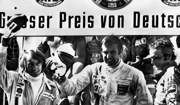 Carlos Reutemann saluda desde el podio tras consagrarse ganador del Gran Premio de Alemania de Fórmula 1, junto al francés Jacques Laffite (2º) y al austriaco Niki Lauda (3º). Nürburgring, 3 de agosto de 1975. - Sputnik Mundo