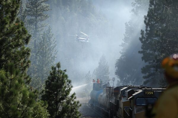La mayoría de los incendios se registraron en los estados de Montana (18), Idaho (17), California (9) y Oregón (9). En la foto: Los bomberos protegen las vías e intentan extinguir los incendios forestales en los estados afectados. - Sputnik Mundo