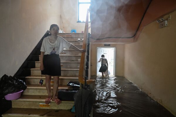 Unas personas caminan en un hotel inundado en Ningbo (China) mientras el tifón In-Fa azota la costa este del país. - Sputnik Mundo