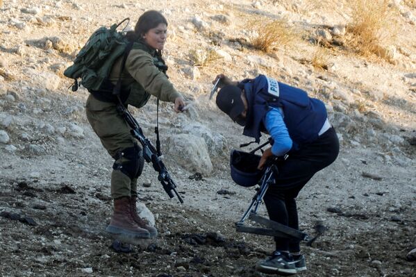 Una soldado israelí rocía gas pimienta a un periodista durante una protesta contra los asentamientos israelíes en Cisjordania. - Sputnik Mundo
