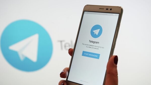 Una persona sostiene un teléfono con la 'app' Telegram en la pantalla - Sputnik Mundo