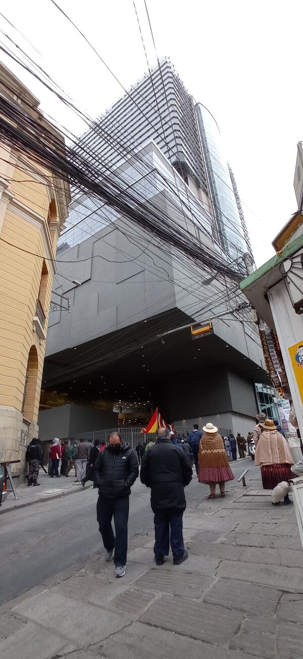 El enorme cubo negro que ya es parte del paisaje paceño coexiste con construcciones centenarias -muchas de las cuales están derruidas- y con la red de teleféricos, que dan un toque futurista a la ciudad. La elegancia posmoderna y ancestral de la nueva Asamblea contrasta con una ciudad plagada por el tráfico vehicular, los cables y un sinfín de obstáculos para las y los peatones El enorme cubo negro que ya es parte del paisaje paceño coexiste con construcciones centenarias -muchas de las cuales están derruidas- y con la red de teleféricos, que dan un toque futurista a la ciudad. La elegancia posmoderna y ancestral de la nueva Asamblea contrasta con una ciudad plagada por el tráfico vehicular, los cables y un sinfín de obstáculos para las y los peatones - Sputnik Mundo