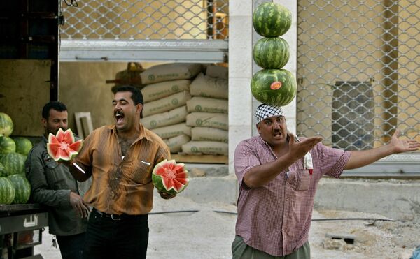 Un vendedor de frutas hace equilibrios con varias sandías en la cabeza para atraer a los clientes en Palestina. - Sputnik Mundo