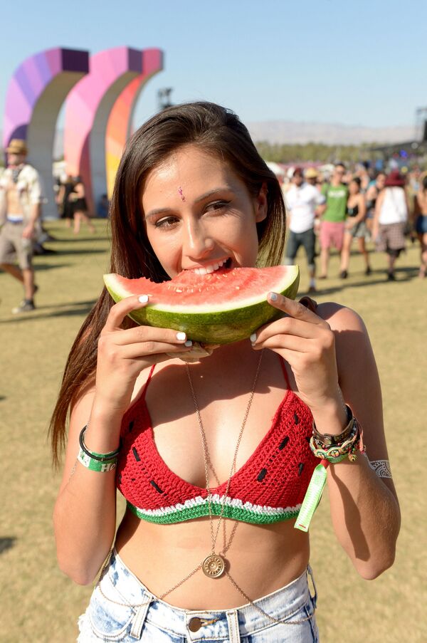 Una asistente al festival musical Coachella disfruta de una sandía. - Sputnik Mundo