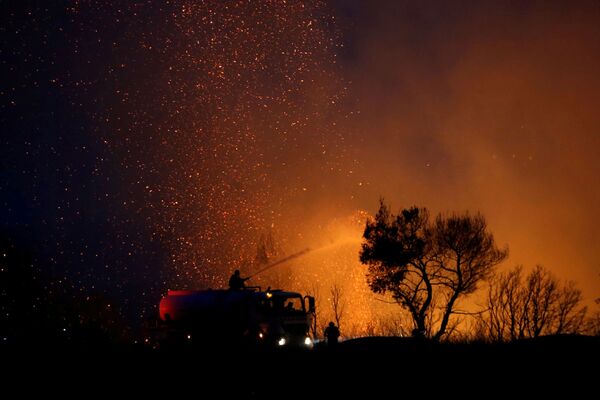 Un equipo de bomberos intenta sofocar un incendio forestal en Varympompi. - Sputnik Mundo