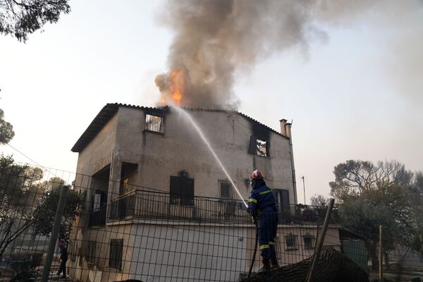 Un bombero intenta apagar una casa en llamas en Varympompi, al norte de Atenas. - Sputnik Mundo