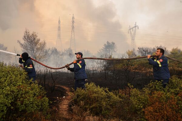 Unos bomberos voluntarios portan una manguera. - Sputnik Mundo