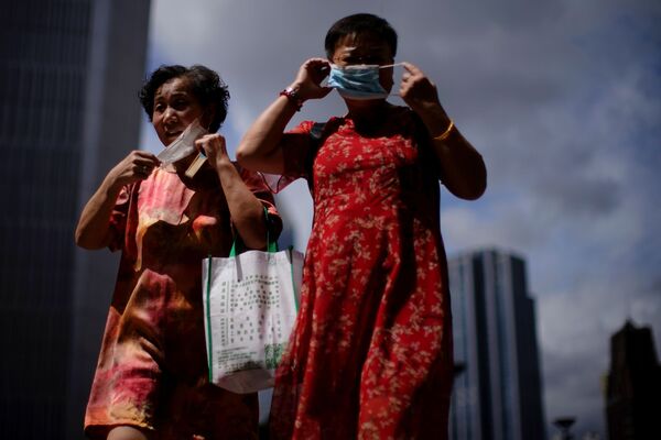 El 3 de agosto, las autoridades de Wuhan notificaron tres casos de infección confirmados y cinco asintomáticos. En la foto: dos mujeres se ajustan sus mascarillas mientras caminan por la calle, tras los nuevos casos de coronavirus, en Shanghái, China. - Sputnik Mundo