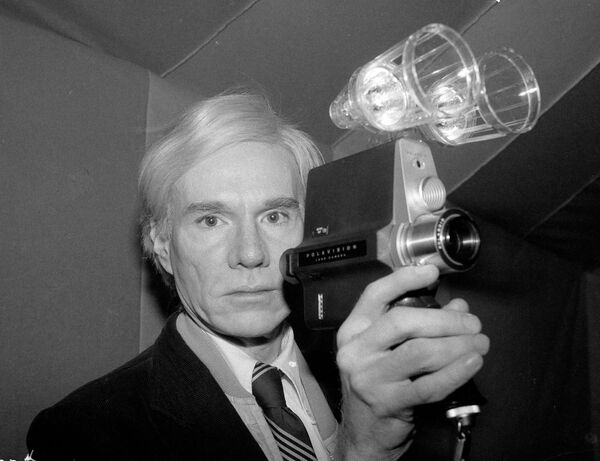 A lo largo de la década de los 60, Warhol pasó a dedicarse cada vez más a la carrera de cineasta. Sus películas, a menudo clasificadas como alternativas, son conocidas por el erotismo inventivo, la falta de tramas y la duración desmesurada.En la foto: Andy Warhol posa con una de las cámaras de película de Polaroid. - Sputnik Mundo