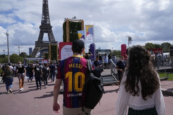 Un visitante viste una camiseta de fútbol del FC Barcelona con el 10 de Lionel Messi mientras camina frente a la Torre Eiffel, en París - Sputnik Mundo