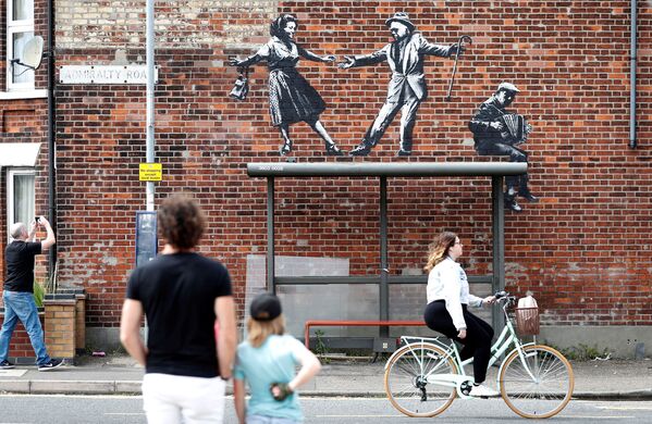 Unas personas observan una obra de arte callejero que se cree que es de autoría de Banksy en Great Yarmouth (Reino Unido) el 8 de agosto. - Sputnik Mundo